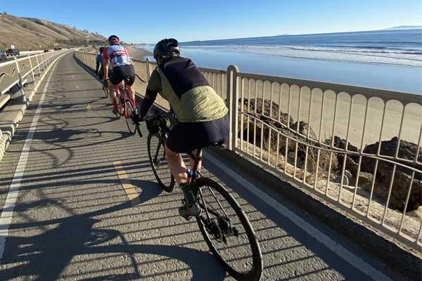 Three bicyclists riding by the ocean